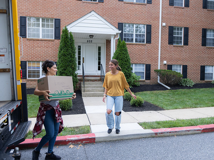Two people carrying boxes from a moving truck