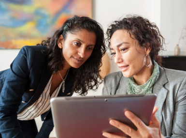 Two businesswomen conversing and examining an iPad
