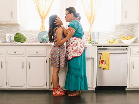 Adult hugging child in a kitchen