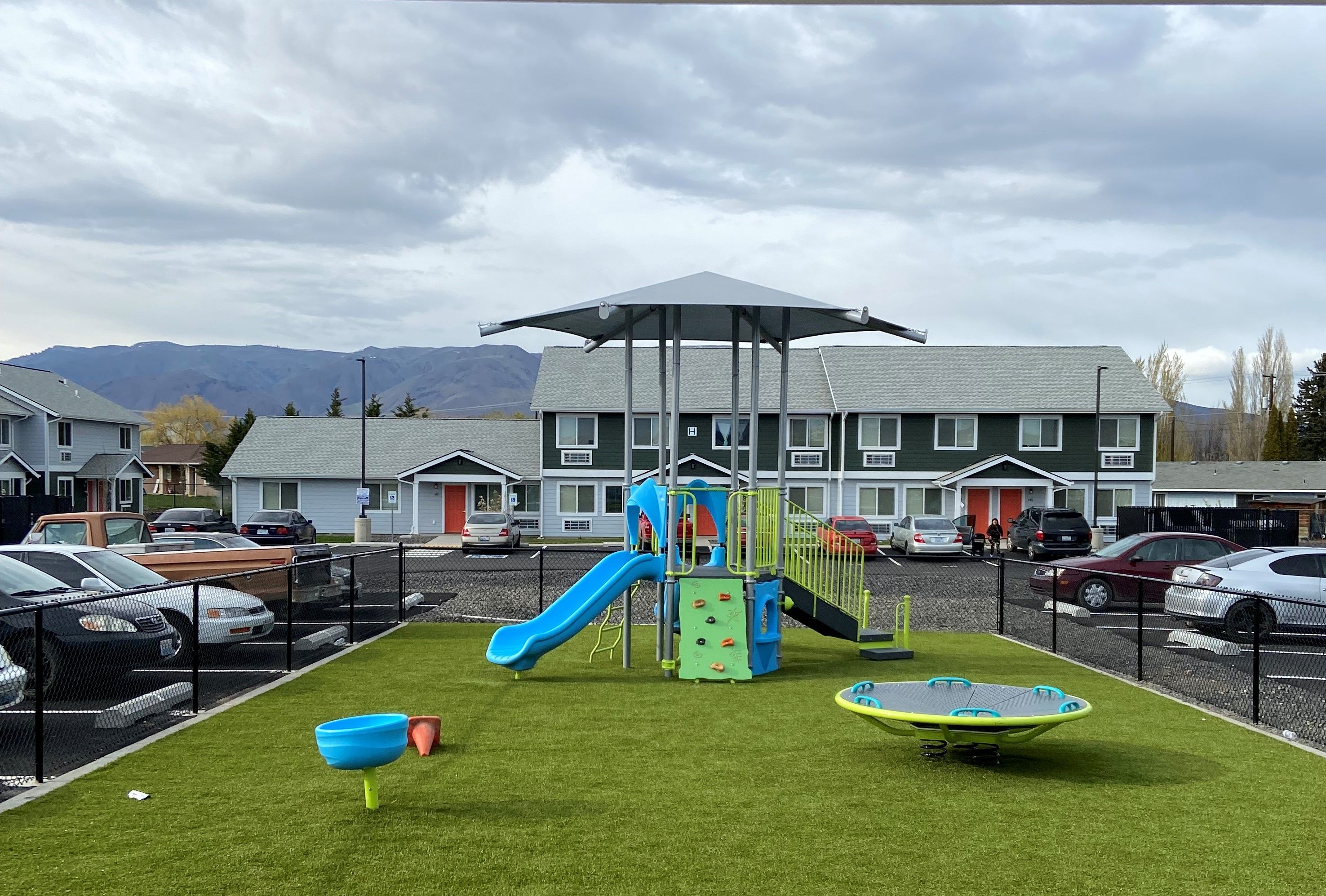 Colorful playground surrounded by rental units with mountains in the distance