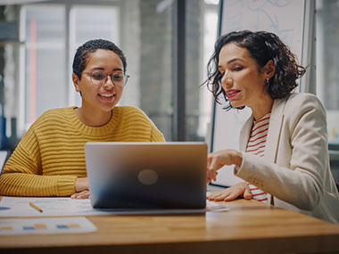 Team member with a mentor coaching them on a laptop