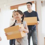 a family smiling and moving in with boxes