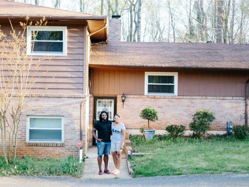 couple smiling and posing for a picture at the entrance of the house