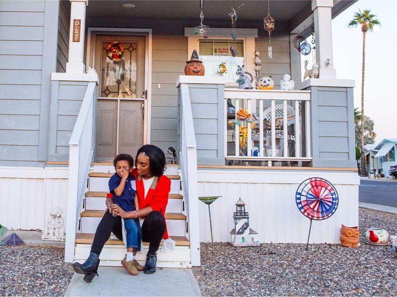 mother sitting with her young child talking at the entrance of the house