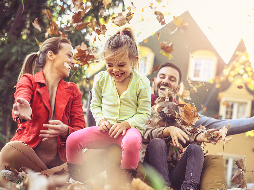 Family playing in the leaves in their front yard